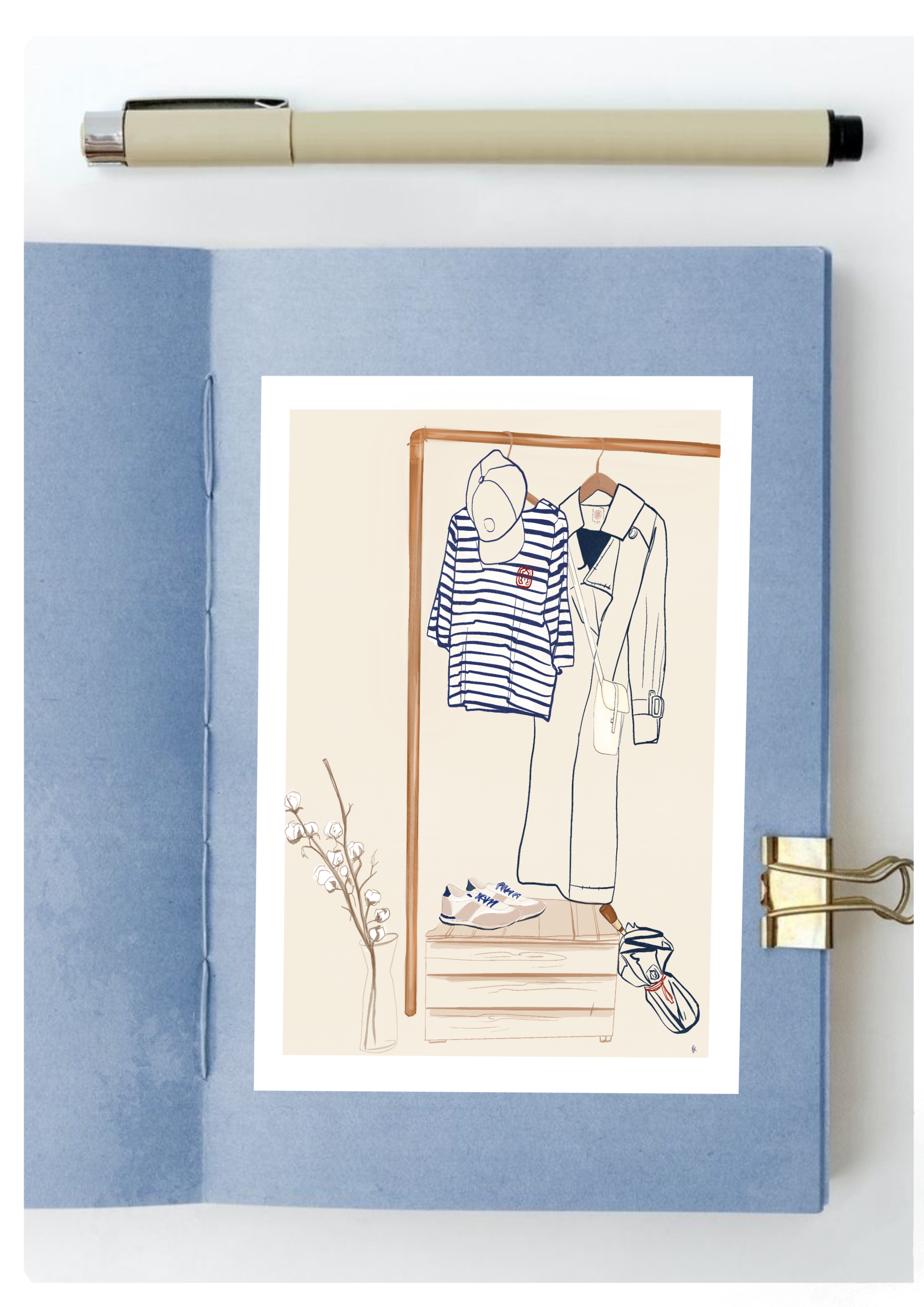 Mockup mettant en scène une illustration élégante représentant une marinière, un trench-coat et des accessoires dans un carnet bleu, accompagné d’un stylo beige et d’un décor minimaliste.